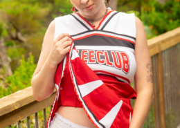 Wearing a cheer uniform, Lola teasingly lifts her skirt showing off her pull-on style diaper.