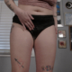 Olivia's sexy black incontinence panties leak heavily as she pees in them.