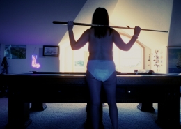 Rear view of Alisha playing pool while wearing only a diaper.